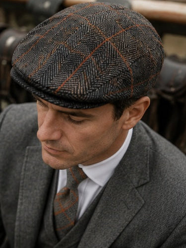 Man wearing a patterned flat cap and suit with a blurred background